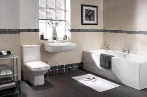 High contrast bathroom with dark tiles and light bathmat, dark towel on white tub.
