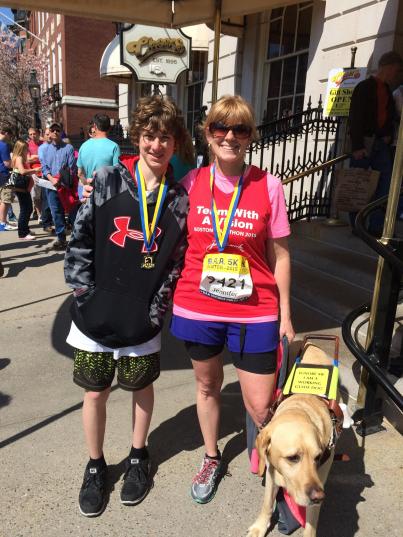 Jen Buchanan, her son Ryan, and her guide dog Keating pose outside Cheers in Boston after both Jen and Ryan ran in the B.A.A. 5K 2015
